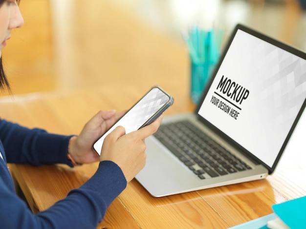 PSD vista lateral da mulher de negócios usando o smartphone enquanto trabalha com a maquete do laptop