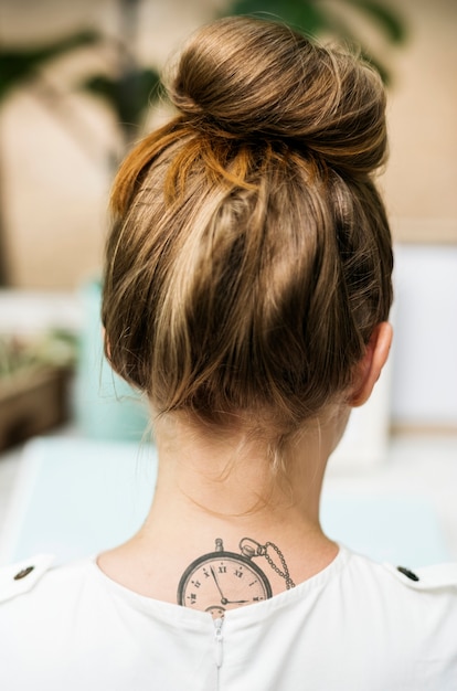 Vista posterior de la mujer con tatuaje en el cuello