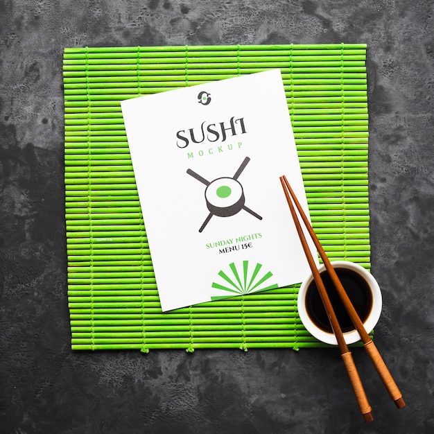 Vista superior de pauzinhos com molho de soja no rolo de bambu para sushi