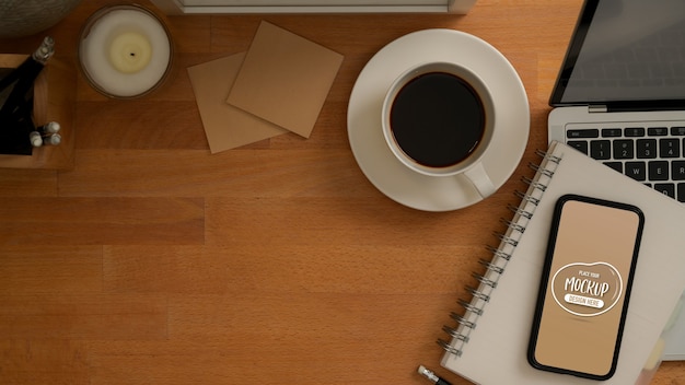 PSD vista superior de la mesa de trabajo con maqueta de teléfono inteligente, computadora portátil, taza de café, papelería y espacio para copiar
