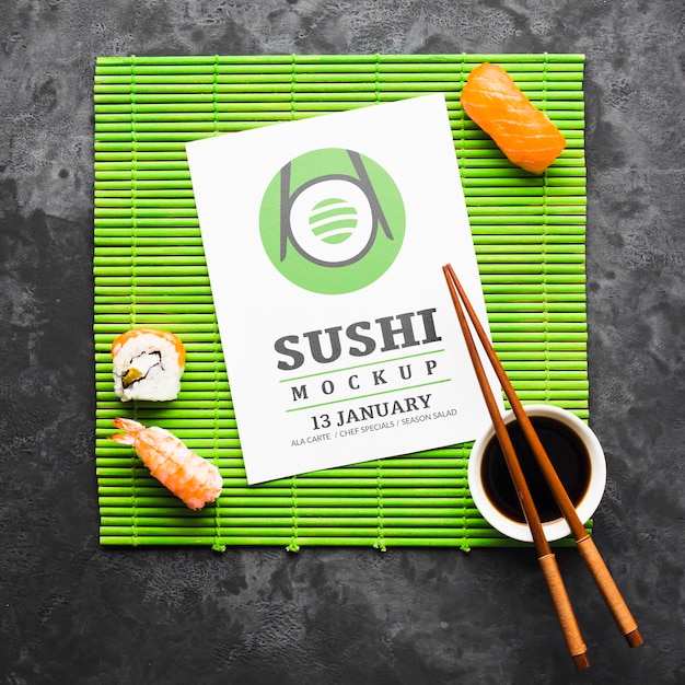 Vista superior de sushi con palillos y salsa de soja en rodillo de bambú