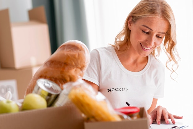 Volontario femminile di smiley annotare il cibo per le scatole di donazione