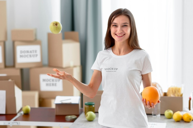 Vorderansicht des weiblichen Freiwilligen des Smileys, der Apfel in die Luft wirft