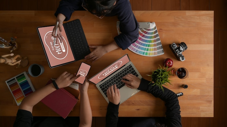 PSD vue de dessus de l'équipe de concepteurs travaillant ensemble sur leur projet avec une maquette d'appareils numériques