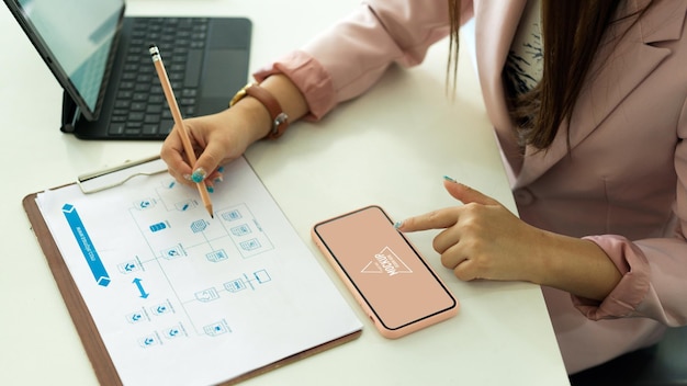 Vue de dessus de la femme d'affaires travaillant avec la paperasse et l'écran de maquette de smartphone