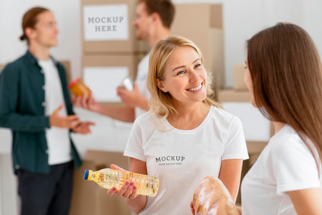 Weibliche Freiwillige, die Spendenboxen vorbereiten, und Mann, der Essen spendet