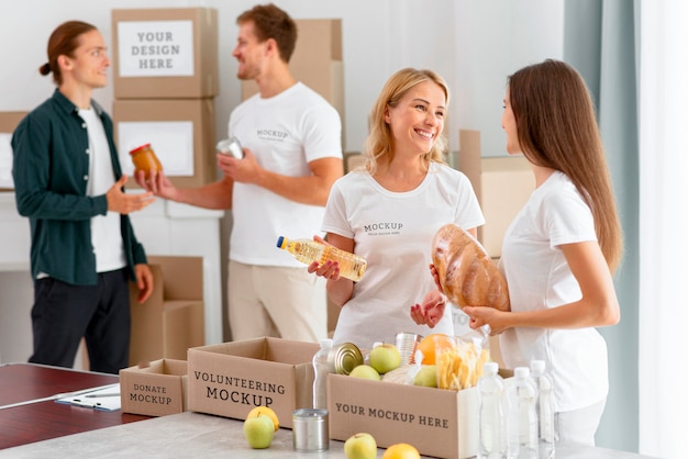 Weibliche Freiwillige, die Spendenboxen vorbereiten, und Mann, der Proviant spendet