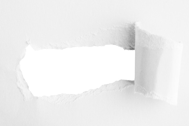 Weißes, dickes Papier, in der Mitte zerrissen, mit einem leeren Loch und einem leeren Hintergrund dahinter.