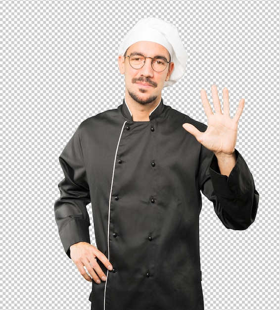 Young chef making a number five gesture