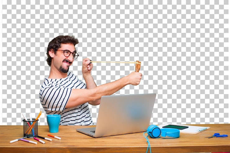 PSD young crazy graphic designer on a desk with a laptop and with a slingshot