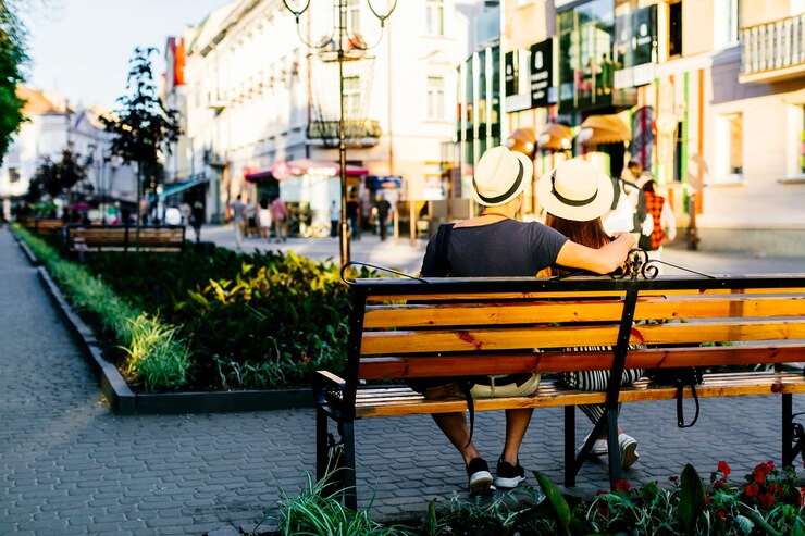 Ücretsiz Fotoğraf bankta oturan turist çiftin arka görünümü