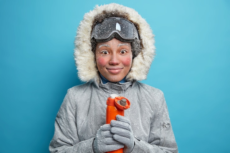 Ücretsiz Fotoğraf cheerful frozen woman with red face during frost smiles pleasantly has coffee break after snowboarding activity wears warm winter clothes holds thermos with hot beverage.