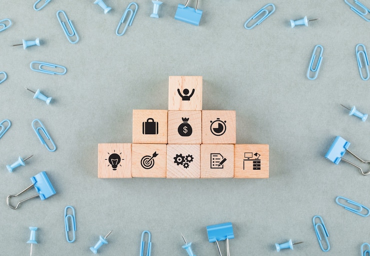 Ücretsiz Fotoğraf conceptual of business office with wooden blocks with icons, paperclips, binder clips top view.