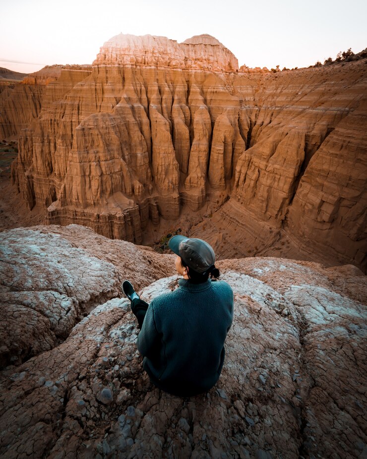 Ücretsiz Fotoğraf female sitting on the edge of the rock with amazing high rocky mountains
