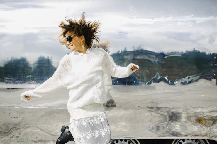 Ücretsiz Fotoğraf girl wearing white clothes jumps next to glimmering vehicle 