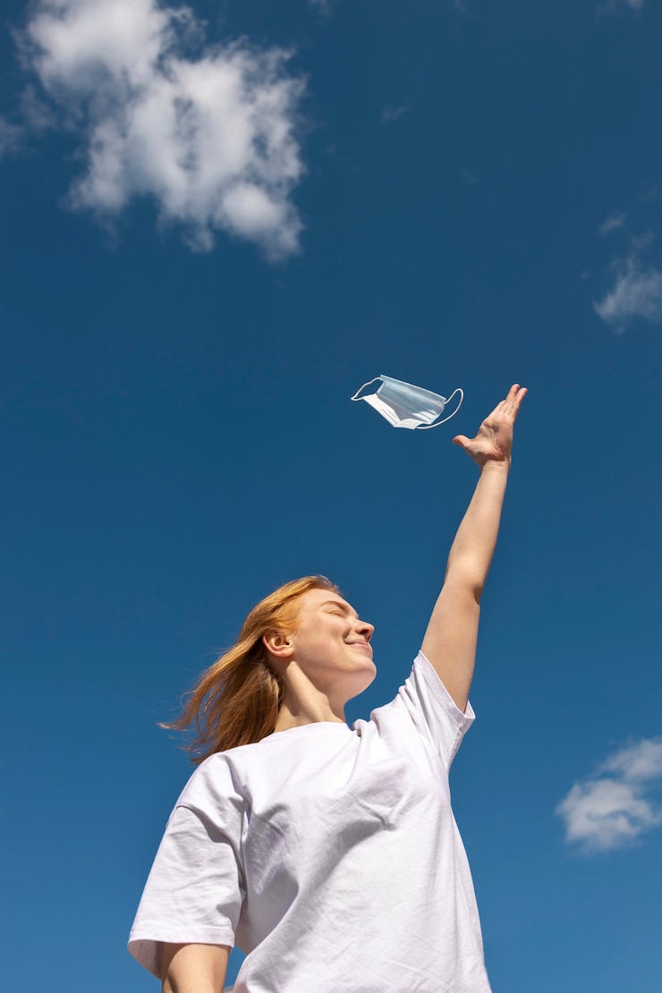 Ücretsiz Fotoğraf low angle smiley woman holding face mask