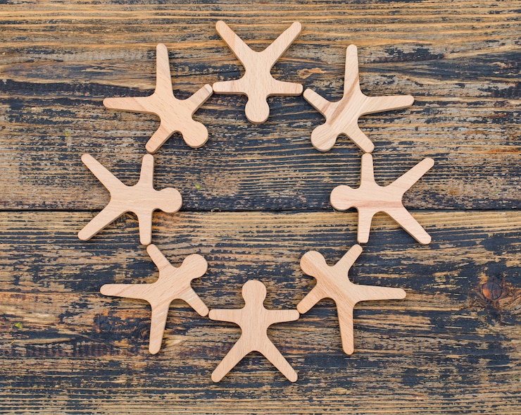 Ücretsiz Fotoğraf marketing concept with wooden figures of person stand in circle on wooden background flat lay.