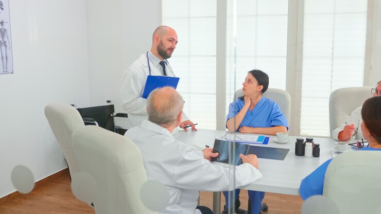Ücretsiz Fotoğraf medical practitioner presenting diagnosis to colleagues holding clipboard during briefing with coworkers. clinic expert therapist talking with colleagues about disease, medicine professional