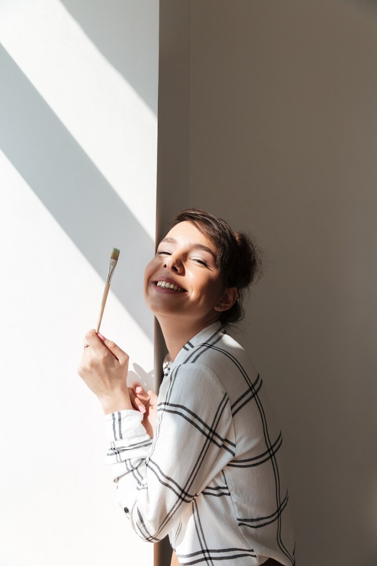 Ücretsiz Fotoğraf portrait of a smiling woman artist holding painbrush and posing