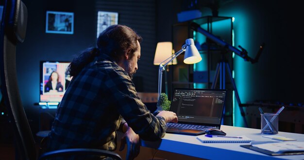 Programmer writes code on laptop screen while in apartment office using Java
