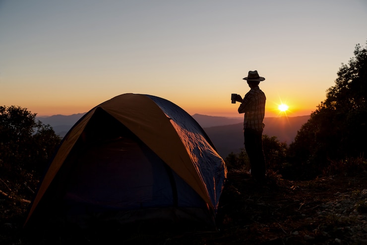 Ücretsiz Fotoğraf silhouette of happy man with holding coffee cup stay near tent around mountains 
