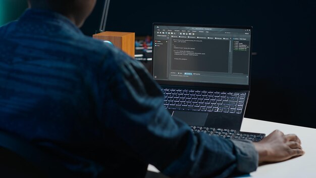 software developer writes code on laptop screen while in apartment office