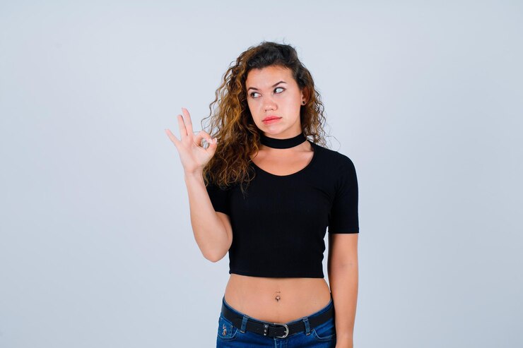 Ücretsiz Fotoğraf young girl is looking left by showing okay gesture on white background