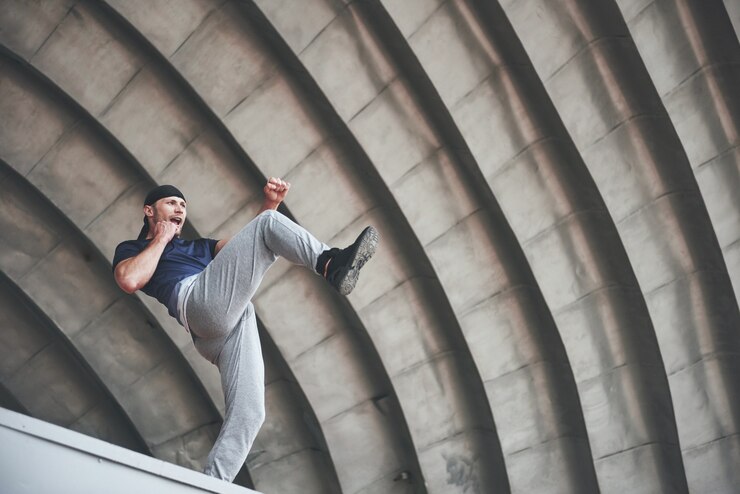 Ücretsiz Fotoğraf young man doing parkour jump in urban space in the city sunny spring summer day.