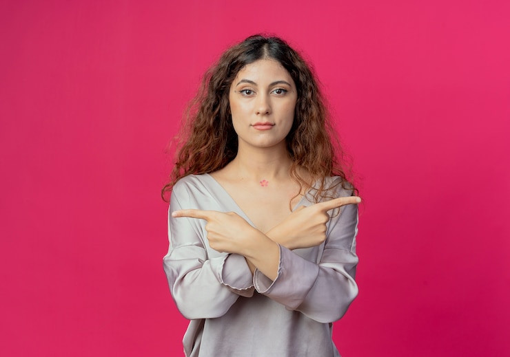 Ücretsiz Fotoğraf young pretty girl points at differents sides isolated on pink wall