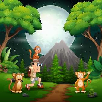 Garçon utilisant des jumelles avec des singes dans une forêt