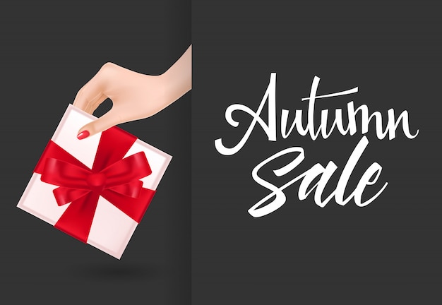 Inscription de vente d&#39;automne avec la main tenant la boîte-cadeau