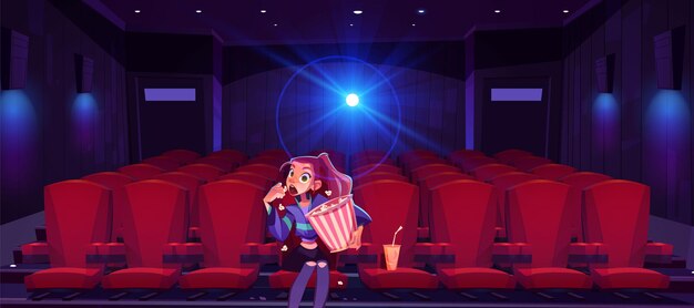 Jeune femme au cinéma fille hypnotisée avec seau de maïs soufflé dans les mains assis seul dans une salle de cinéma