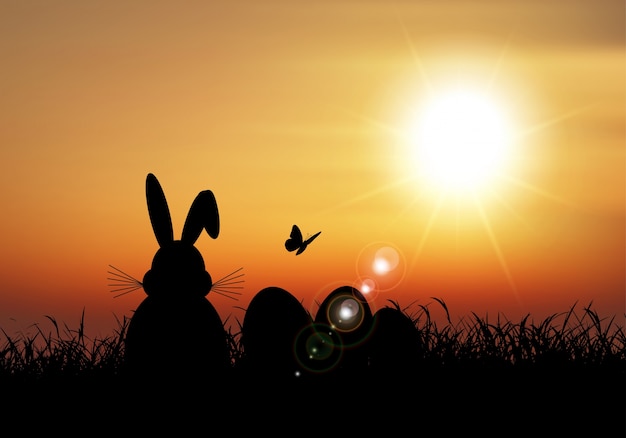 Lapin de Pâques assis dans l&#39;herbe contre un ciel coucher de soleil