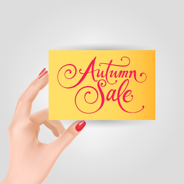 Vecteur gratuit main tenant la carte avec le lettrage de vente d'automne