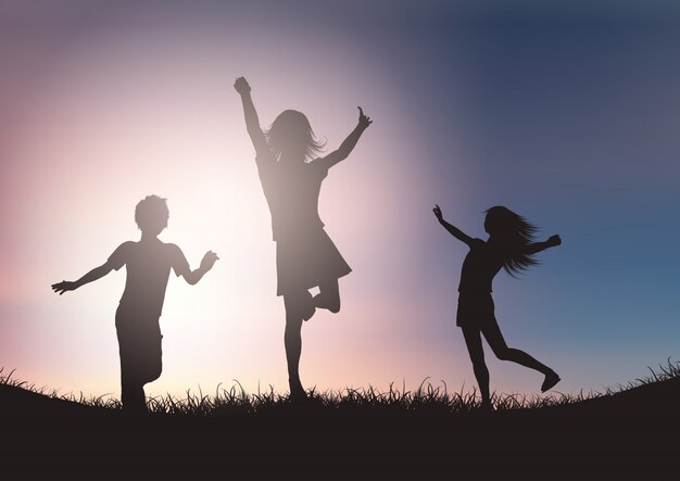 Silhouettes des enfants jouant contre le ciel coucher de soleil