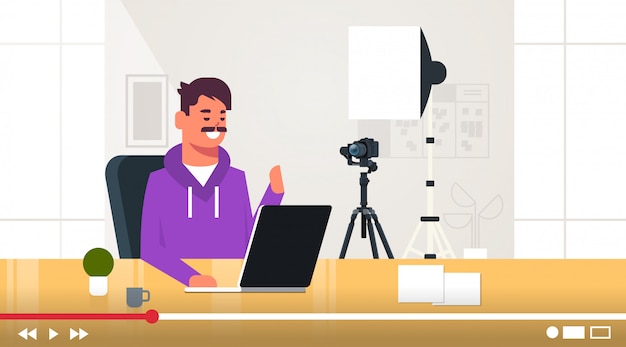 Blogueur de technologie enregistrement vidéo en ligne homme testant un nouveau concept de blog pour ordinateur portable vlogger expliquant l'appareil numérique fonctionnel guy assis au milieu de travail portrait horizontal