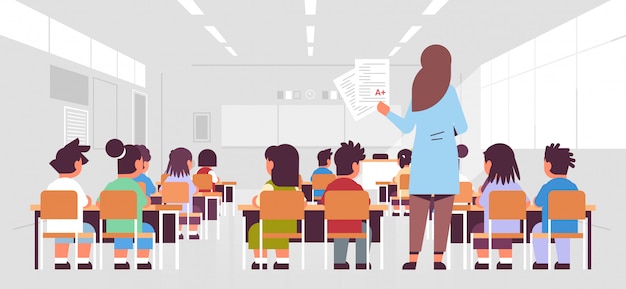 Enseignante tenant des tests avec une bonne classe de vue arrière des élèves groupe assis dans la salle de classe au cours de l'enseignement de l'enseignement concept moderne salle de classe intérieure