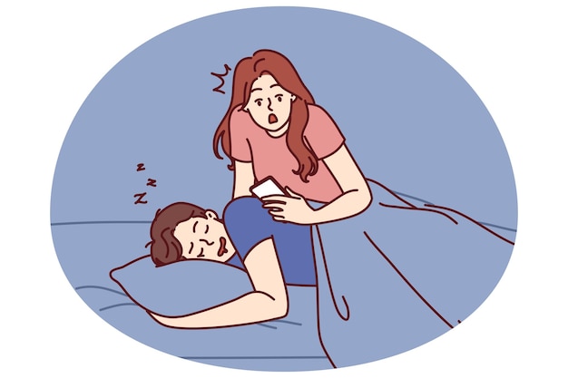 Une femme jalouse lit des SMS dans le téléphone de son petit ami qui dort dans le lit et espionne son mari.