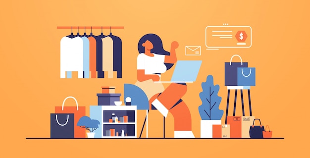 Femme avec ordinateur portable à l'aide de l'application informatique concept de magasinage en ligne grand magasin de mode boutique de vêtements féminins intérieur plat pleine longueur horizontale
