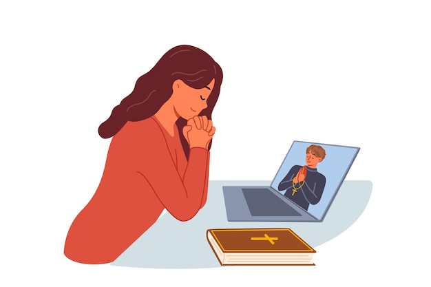 Une femme prie assise devant un ordinateur portable et regarde une diffusion vidéo avec un prêtre de l'église