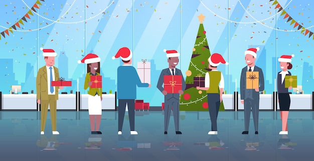 Les Gens D'affaires Célébrant La Fête D'entreprise Mix Race Collègues De Travail En Chapeaux De Père Noël Tenant Des Coffrets Cadeaux Joyeux Noël Bonne Année Vacances Concept Intérieur De Bureau Moderne