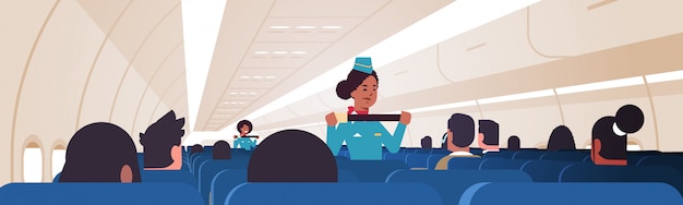 Hôtesse Expliquant Aux Passagers Comment Utiliser La Fixation De La Ceinture De Sécurité En Situation D'urgence Afro-américains Agents De Bord En Uniforme De Démonstration De Sécurité Concept Avion Board Intérieur Horizontal