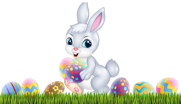 Lapin de Pâques avec des oeufs de Pâques décorés dans un champ