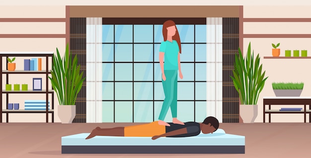 Vecteur masseuse en uniforme debout sur le dos du patient faisant un traitement de guérison guy ayant un massage concept de thérapie manuelle moderne spa salon studio intérieur pleine longueur horizontale