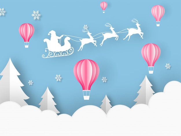 Papier Coupé Style Ballons à Air Chaud, Arbre De Noël, Flocons De Neige Et Silhouette Santa Traineau Traineau De Rennes Sur Fond Bleu Nuageux Pour La Fête De Joyeux Noël.