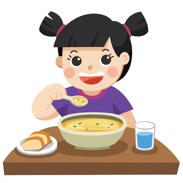 Une petite fille heureuse de manger de la soupe.