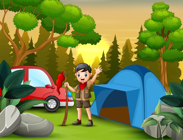 Scout boy avec le drapeau rouge se tenant près d'une tente