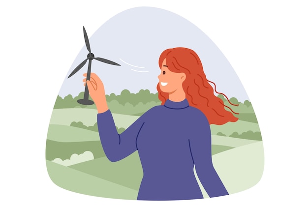 Une turbine éolienne entre les mains d'une femme souriante debout dans la nature et développant des énergies alternatives