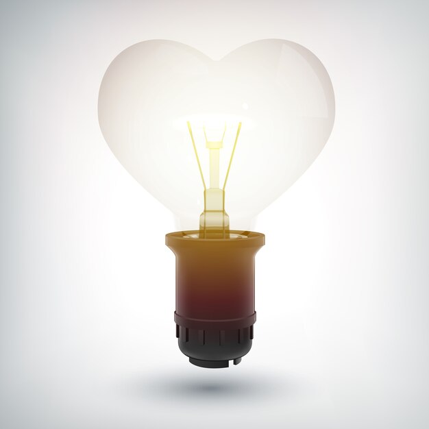 Bombilla incandescente con concepto de base de plástico en forma de corazón como símbolo de amor aislado