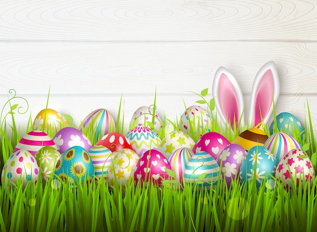 Composición de Pascua con imágenes coloridas de festivos huevos de pascua en la superficie de la hierba verde con ilustración de orejas de conejo